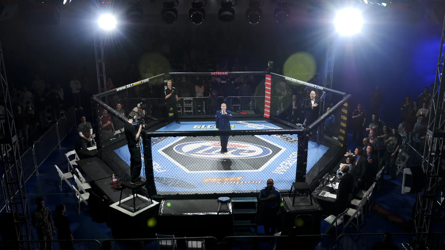 Jaula de artes marciais mistas iluminada no centro de um pavilhão escuro