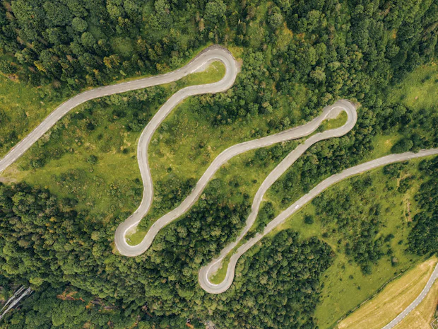 Vista aérea de uma estrada em ziguezague a atravessar uma encosta coberta de floresta