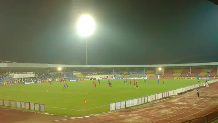 Feixe de luz de um holofote sobre o relvado de um campo de futebol à noite