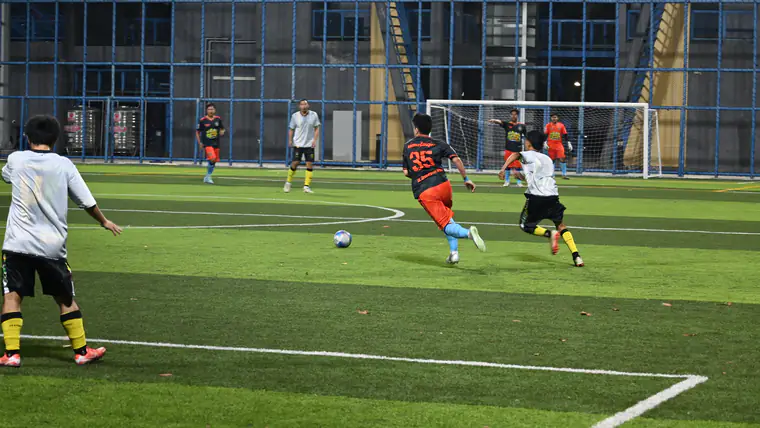 Jogadores disputam a bola num relvado iluminado durante um jogo nocturno