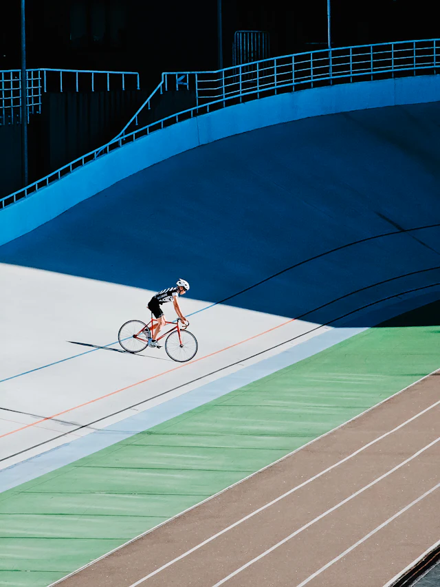 Curva sobreelevada de um velódromo vista de baixo, com a pista em madeira inclinada